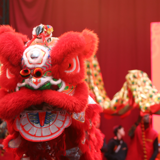 A colorful Chinese lion with a team behind during a festival.