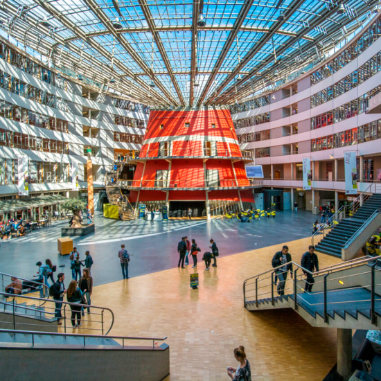 Bright and open indoor area with a glass ceiling, visitors walking around.