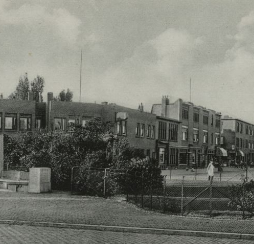 Historic black-and-white photo of Thomsonplein in The Hague, circa 1935, featuring the statue of Major Lodewijk Thomson in the foreground and a view of surrounding residential buildings and shops.