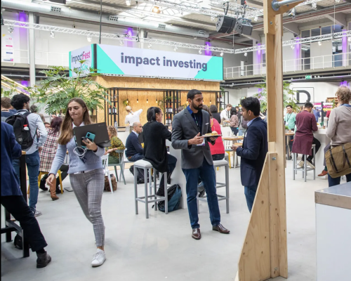 Picture taken at ImpactFest 2022 with a large sign in the background stating 'Impact Investing'.