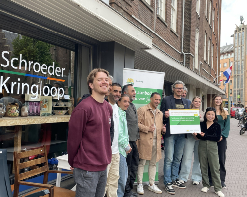 A group of people posing in front of Schroeder Kringloop in The Hague.