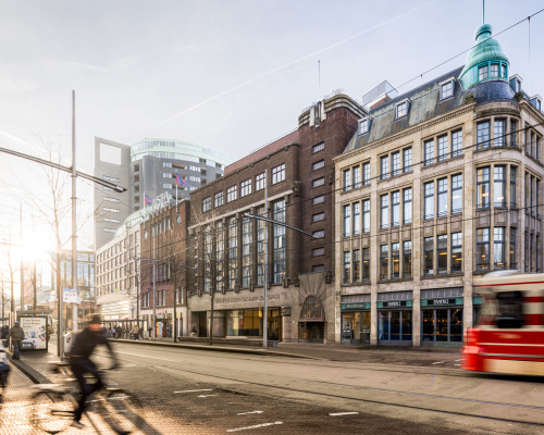 Facade of University Campus Spui with cyclists and tram in the foreground.