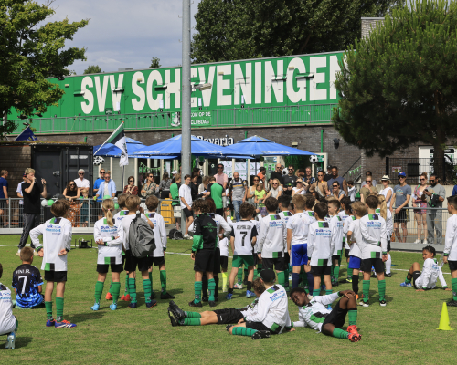 Children in green and white kits training on a football field.