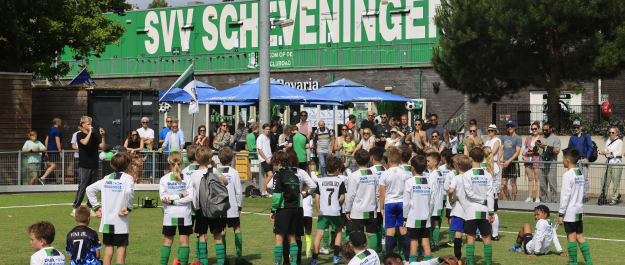 Children in green and white kits training on a football field.