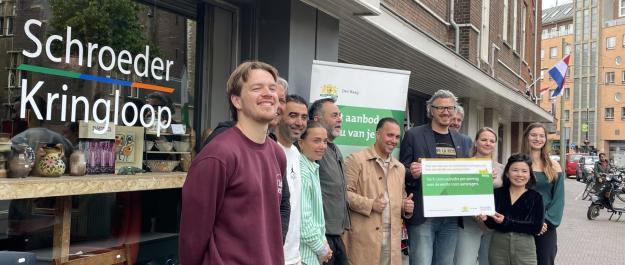 A group of people posing in front of Schroeder Kringloop in The Hague.