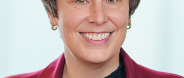 Woman smiling with short brown hair and a red jacket.
