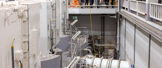 A modern technical space with equipment and visitors on the upper floor.