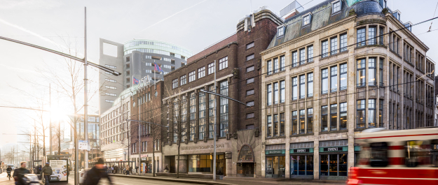 Facade of University Campus Spui with cyclists and tram in the foreground.