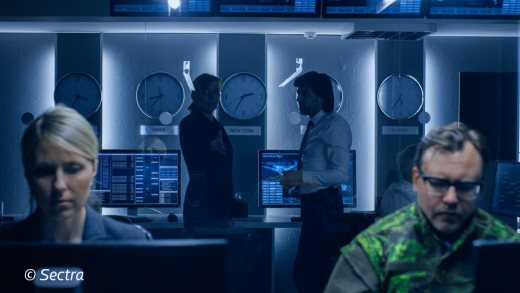 an atmospheric image of sectra displaying people behind a desk and discussing. copyright of Sectra
