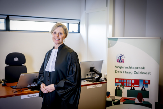 Judge Robine de Lange in official robes at the Wijkrechtspraak Den Haag Zuidwest courtroom, a community court initiative in The Hague improving access to justice for local residents.