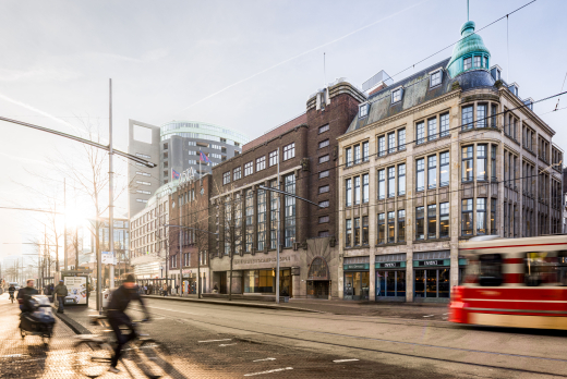Facade of University Campus Spui with cyclists and tram in the foreground.