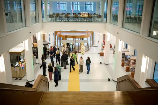 People gathered in a modern space with yellow floor and stairway.